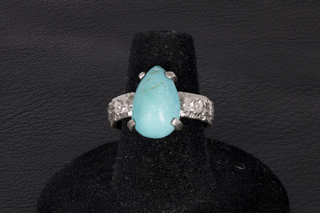 Pear shaped turquoise ring set in sterling silver on a black stand 