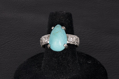 Pear shaped turquoise ring set in sterling silver on a black stand 