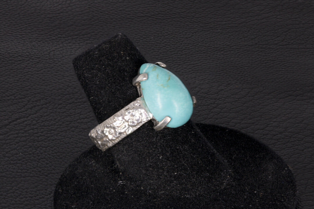 Pear shaped turquoise ring set in sterling silver on a black stand 
