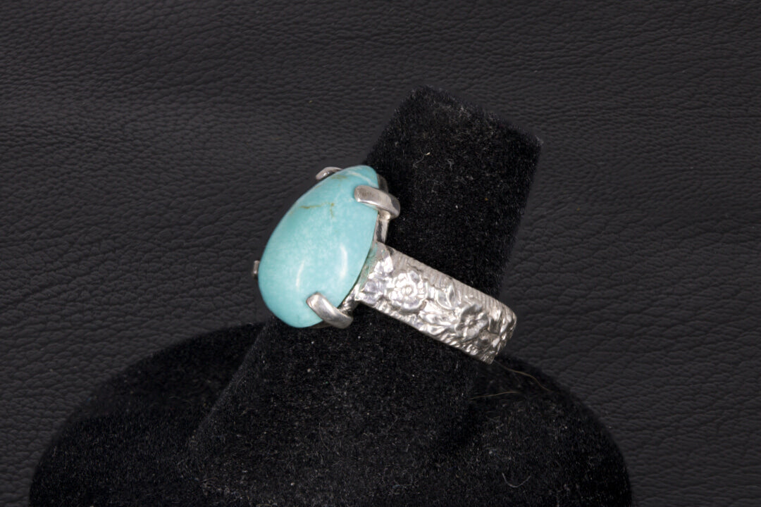 Pear shaped turquoise ring set in sterling silver on a black stand 