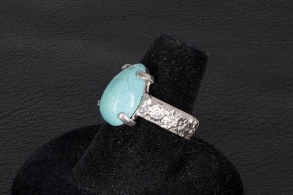 Pear shaped turquoise ring set in sterling silver on a black stand 