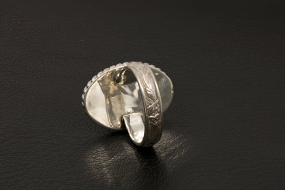 Silver ring with intricate design on a black background back view