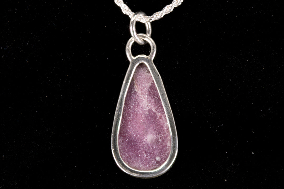 Pink Lepidolite pendant set in sterling silver on a black background back view