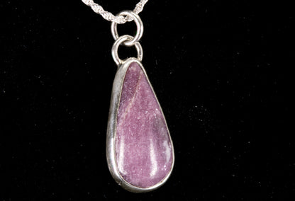 Pink Lepidolite pendant set in sterling silver on a black background right side view