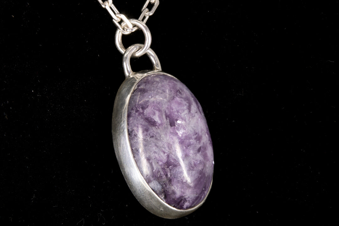Purple Lepidolite pendant on a silver chain against a black background