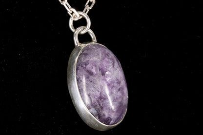 Purple Lepidolite pendant on a silver chain against a black background