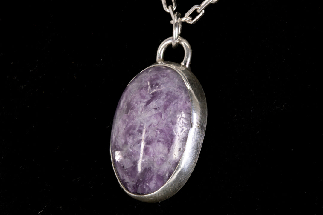 Purple Lepidolite pendant on a silver chain against a black background