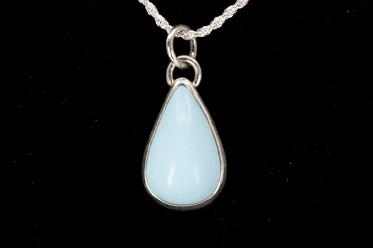 Teardrop-shaped pendant with light blue stone on a black background front view