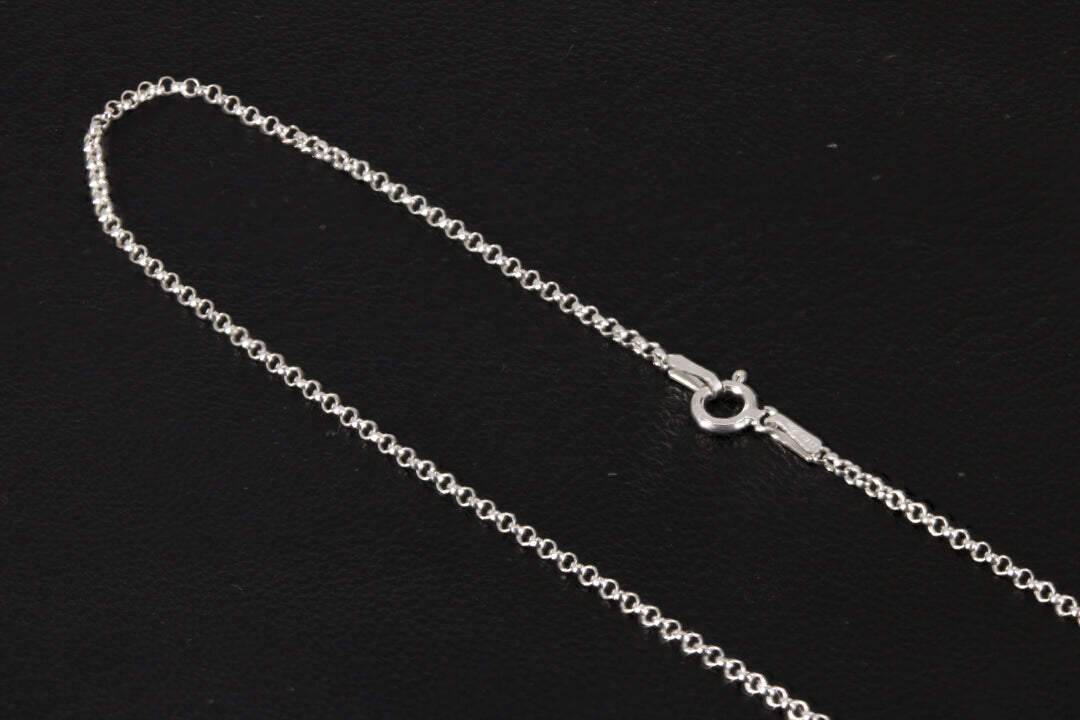 A rolo style sterling silver chain on a black background