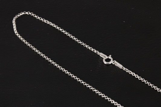 A rolo style sterling silver chain on a black background