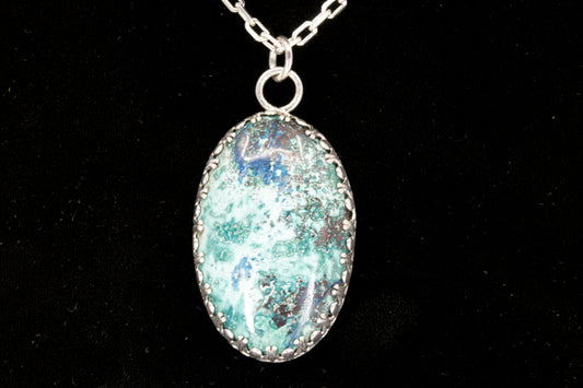 Oval Shattuckite Pendant set in sterling silver on a black background.