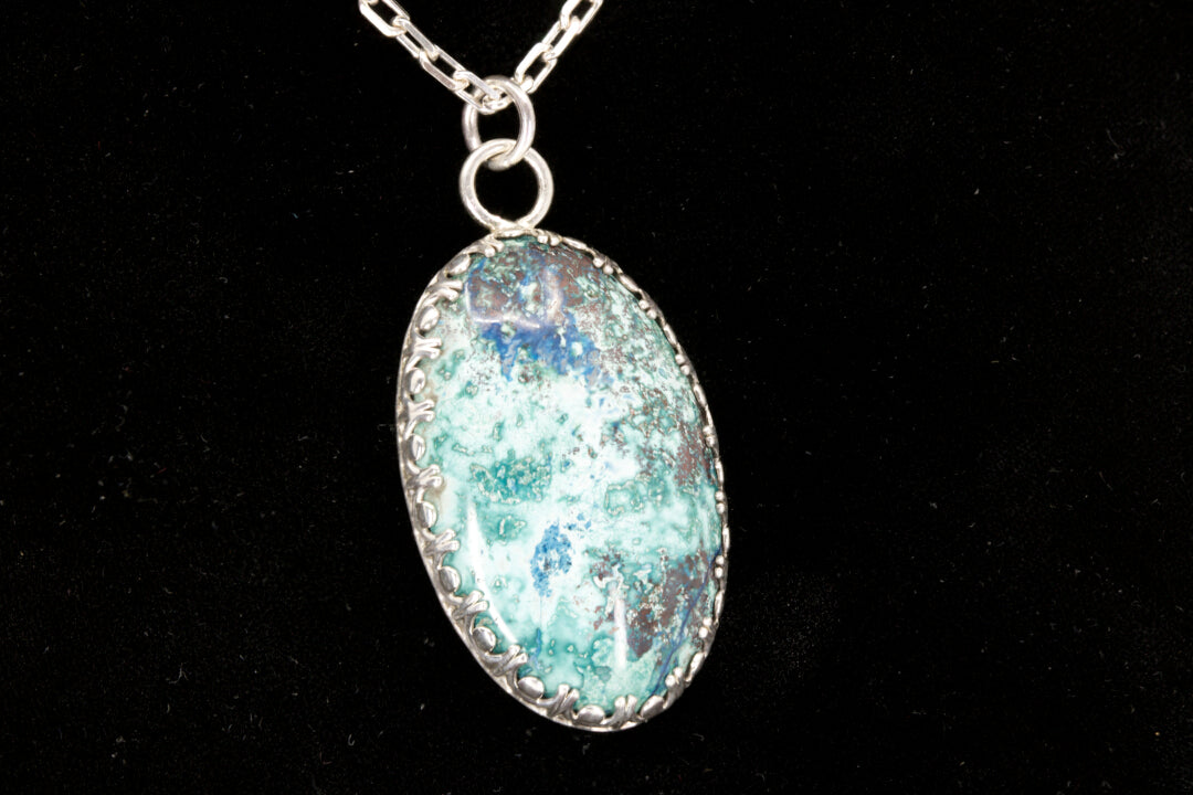 Oval Shattuckite Pendant set in sterling silver on a black background.
