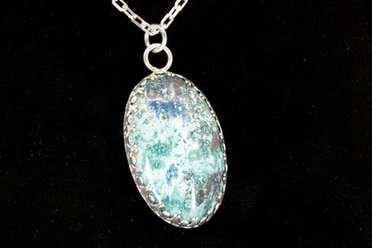 Oval Shattuckite Pendant set in sterling silver on a black background.