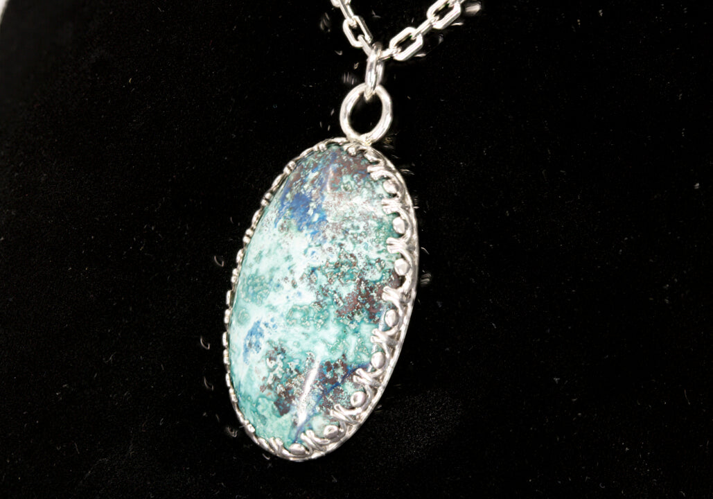 Oval Shattuckite Pendant set in sterling silver on a black background.