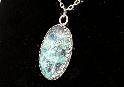 Oval Shattuckite Pendant set in sterling silver on a black background.