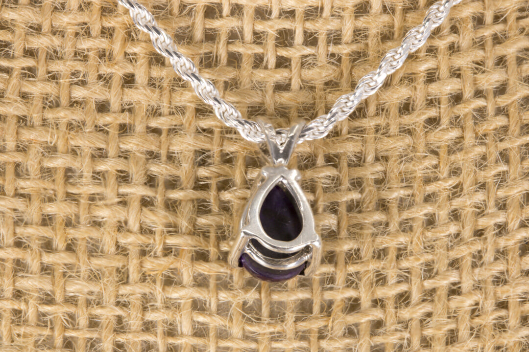 Sugilite pendant necklace on a textured beige background back view