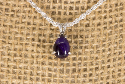 Sugilite pendant necklace on a textured beige background front view